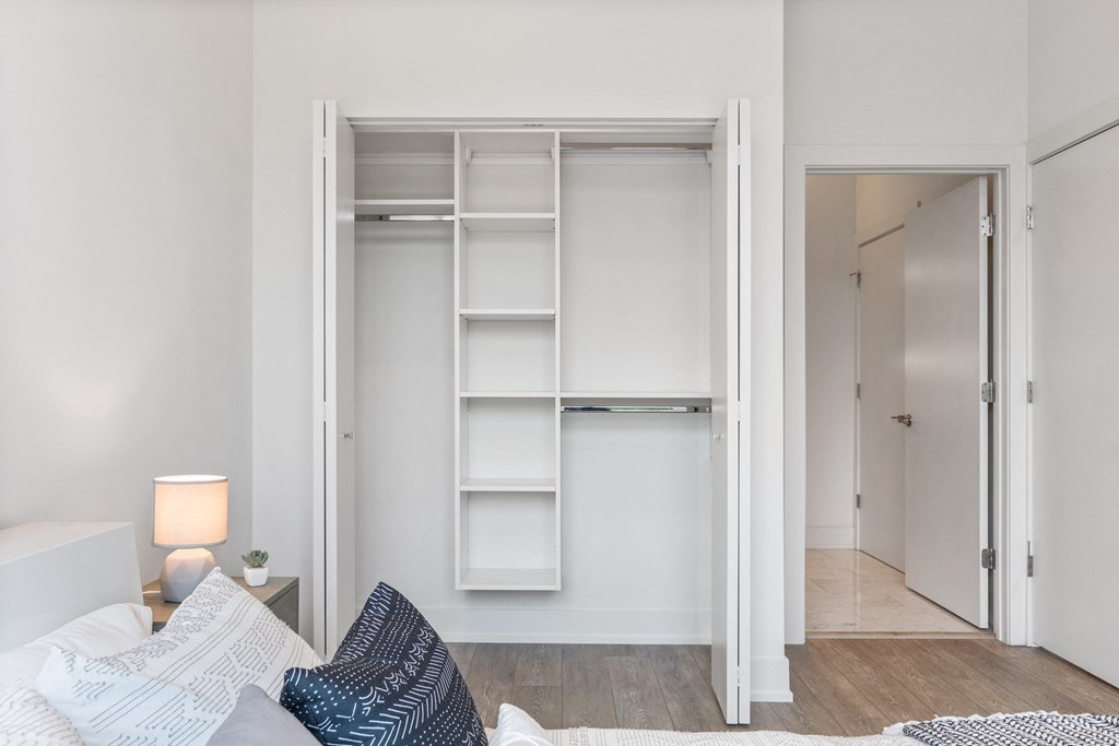 A bedroom with a spacious closets and a bed with blue and white pillows