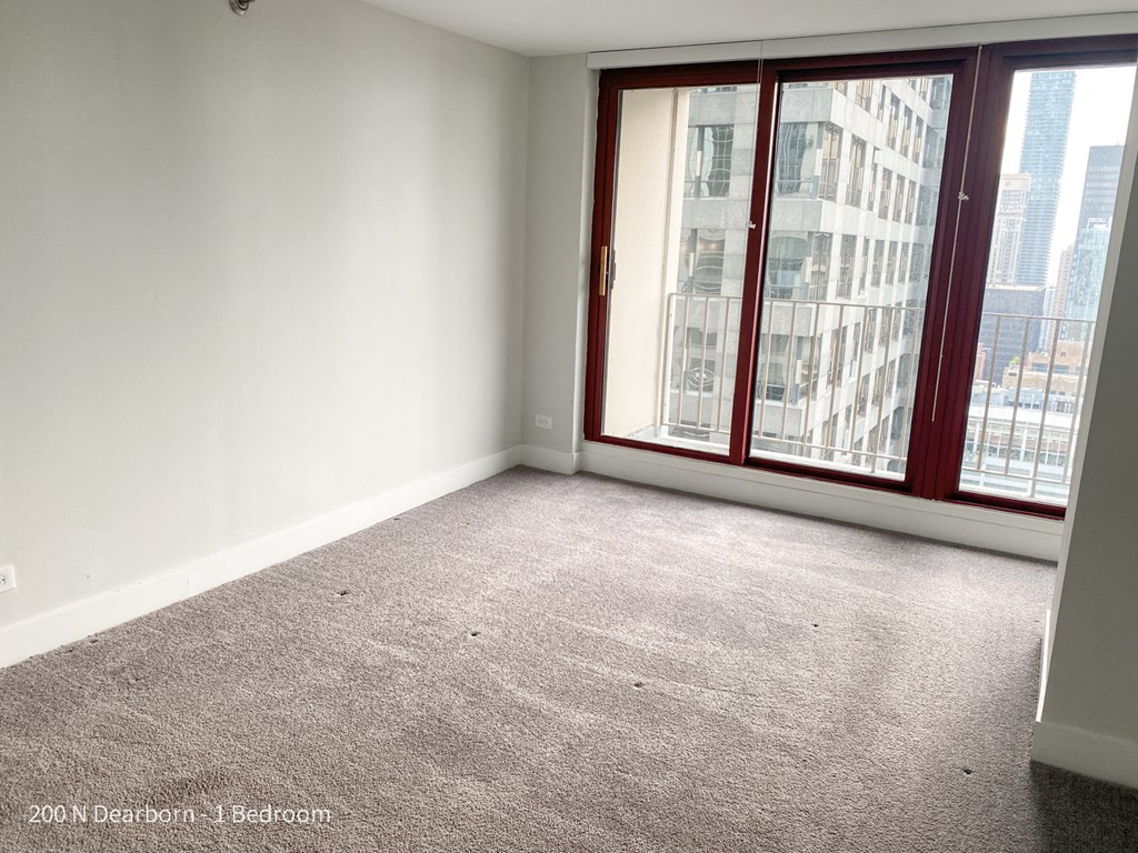 an empty living room with a large window and a carpet