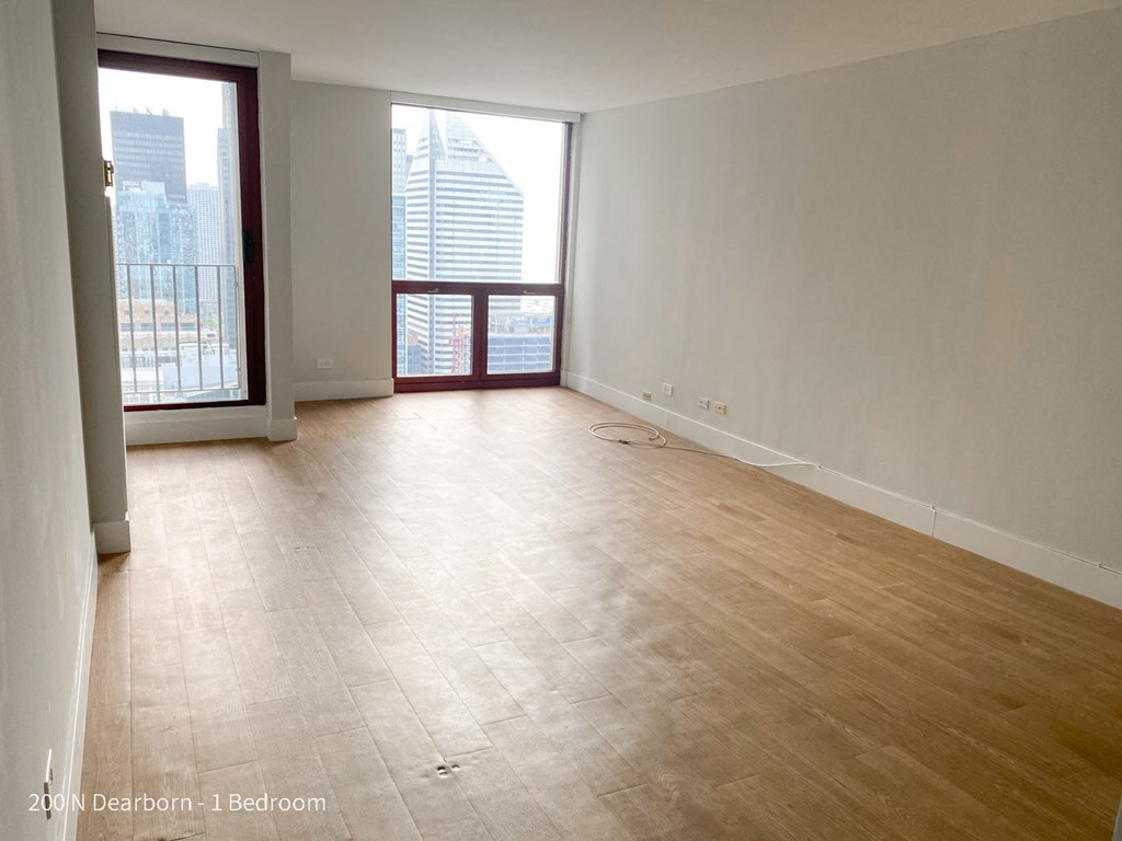 an empty living room with wood flooring and a balcony