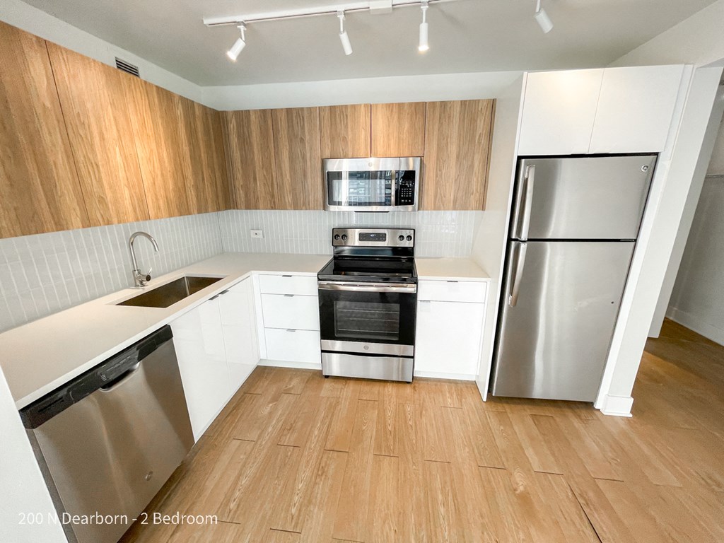 an empty kitchen with white cabinets and stainless steel appliances