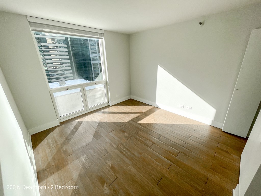 an empty living room with wood floors and a large window