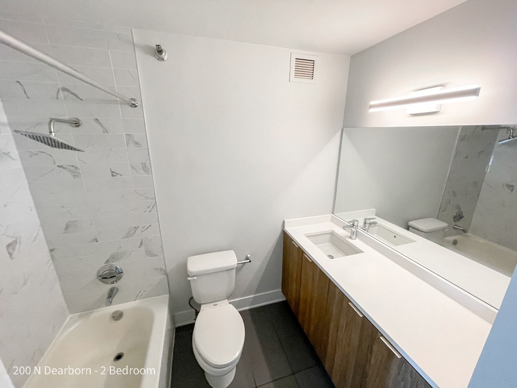 a bathroom with a toilet sink and shower and a mirror