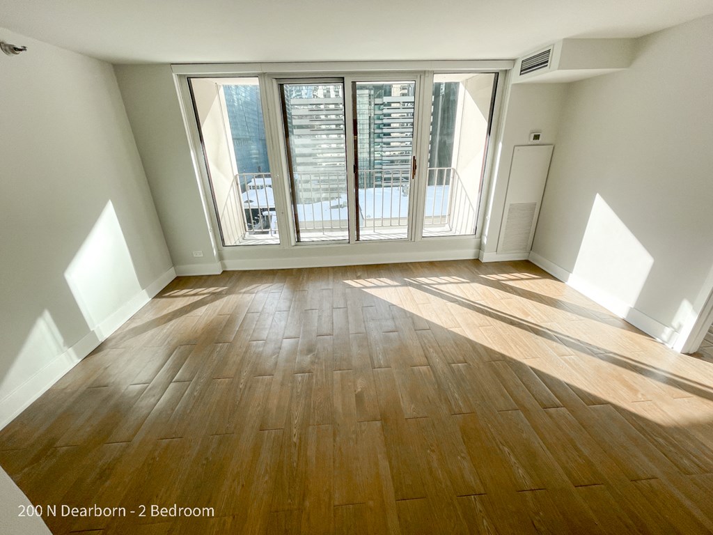an empty living room with hardwood floors and a balcony