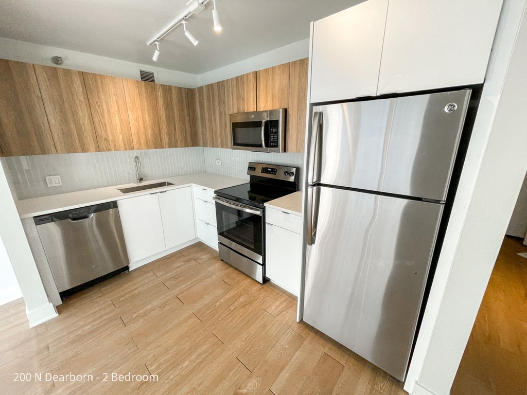 an empty kitchen with stainless steel appliances and white cabinets