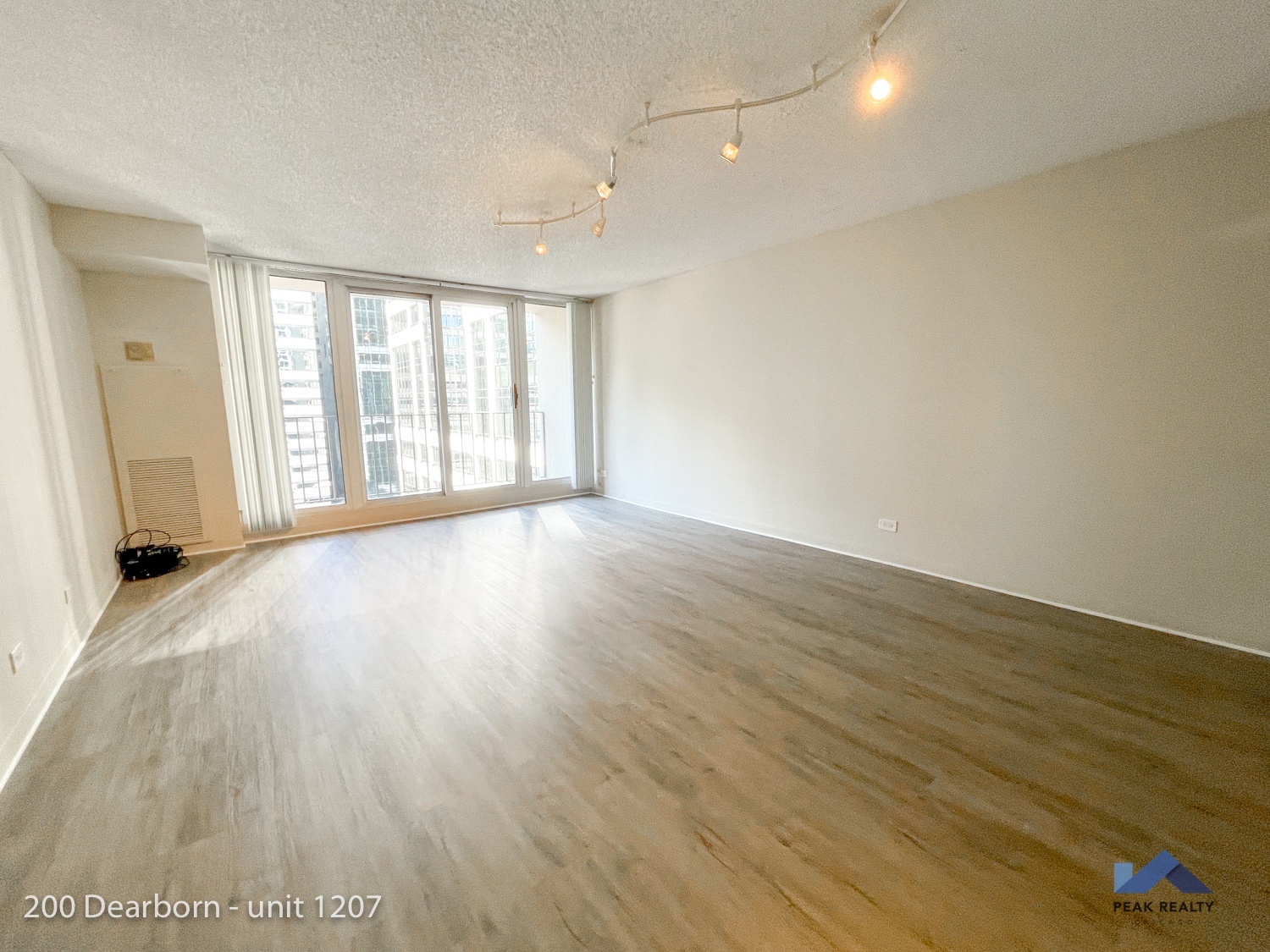 the living room of an apartment with wood flooring and a large window