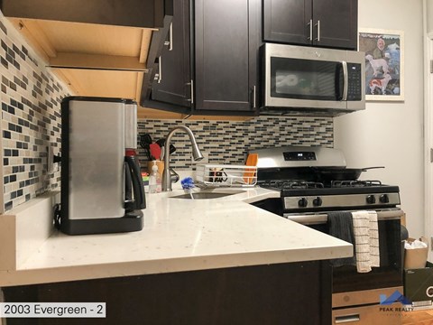 A kitchen with a black fridge and a black microwave above a white counter.