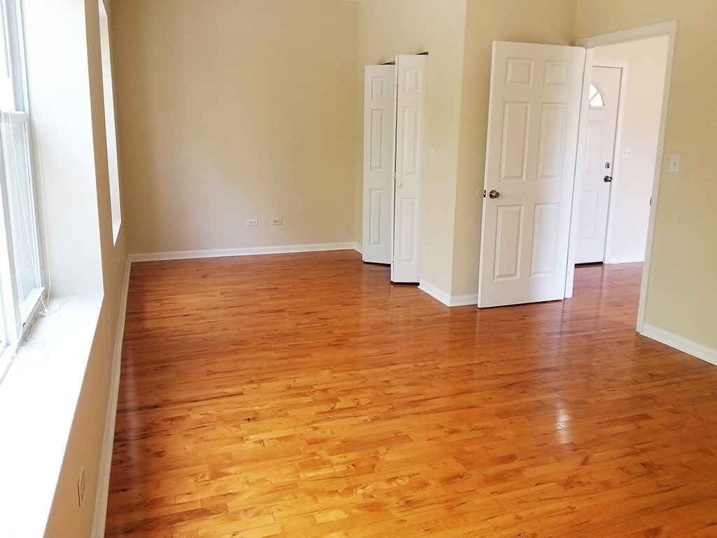 an empty living room with wooden floors and white doors