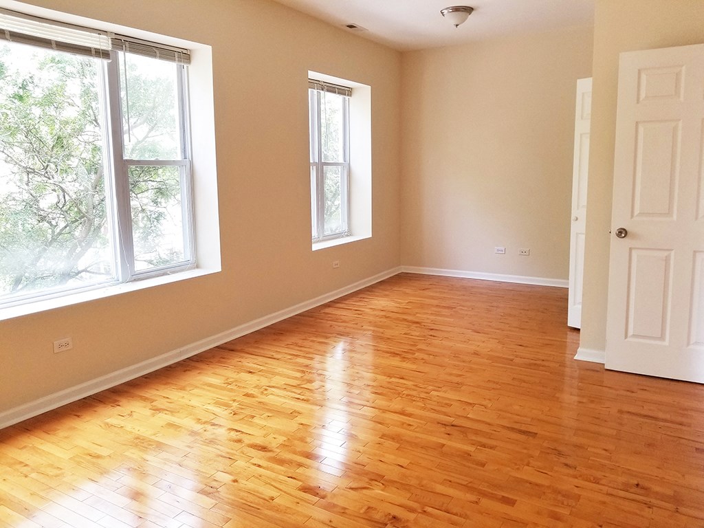 an empty living room with wooden floors and windows