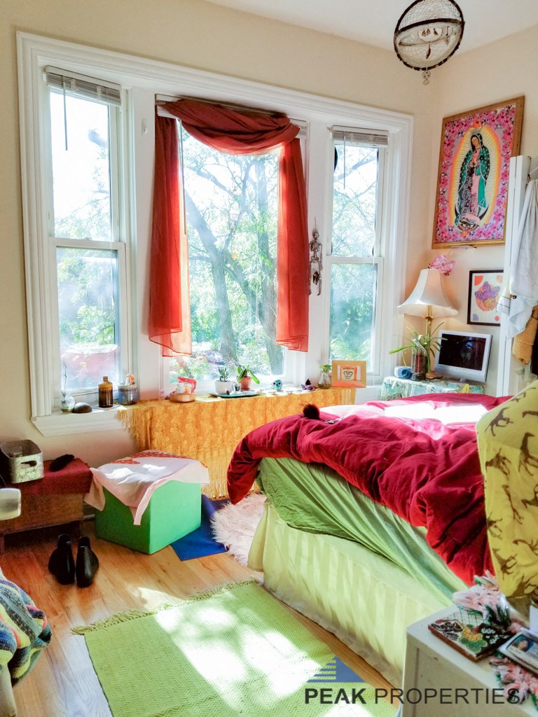 a bedroom with a bed and a window with red curtains