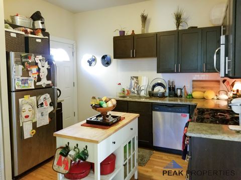 a kitchen with black cabinets and a white island and a refrigerator