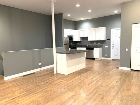 an open kitchen and living room with wood flooring and gray walls