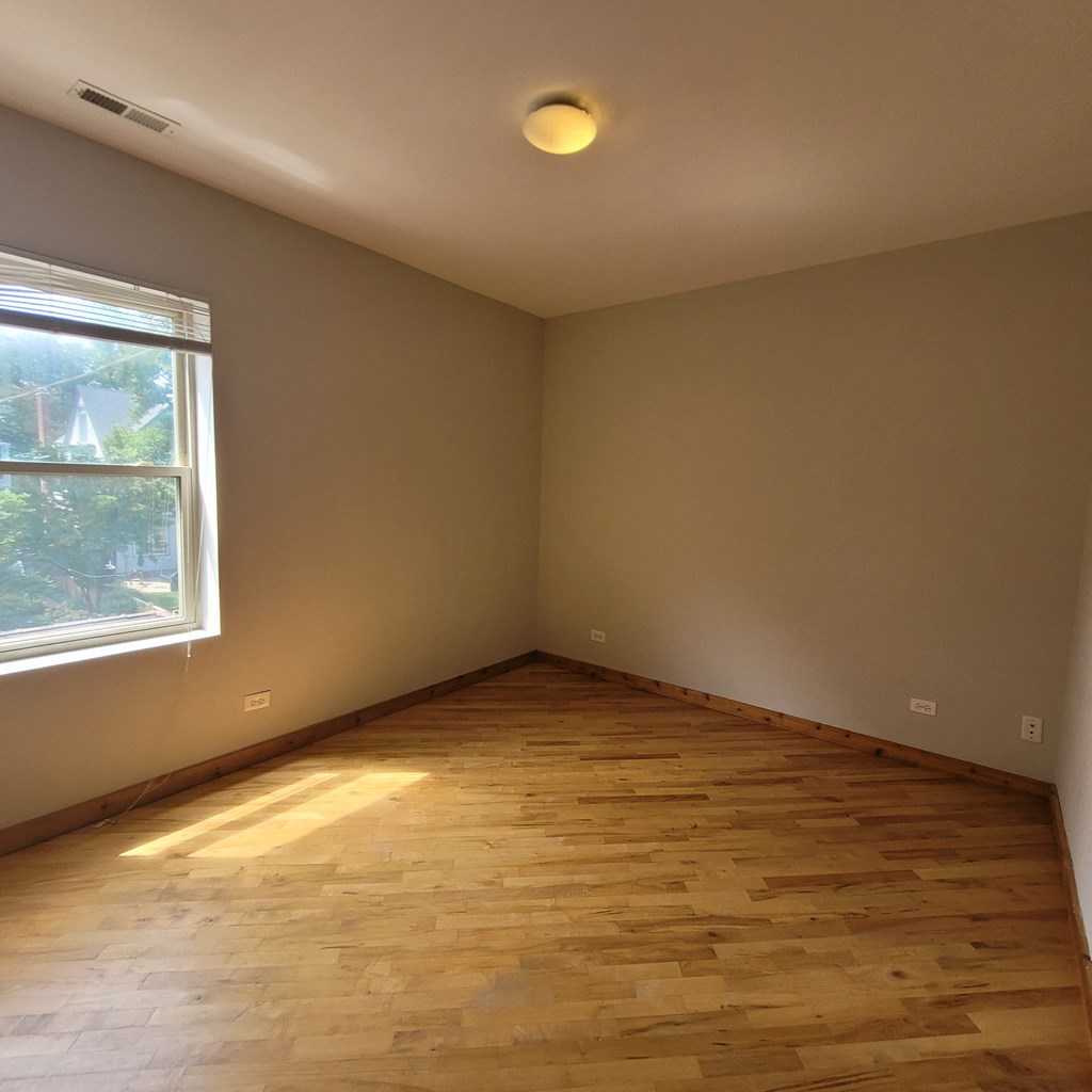 an empty room with wooden floors and a window