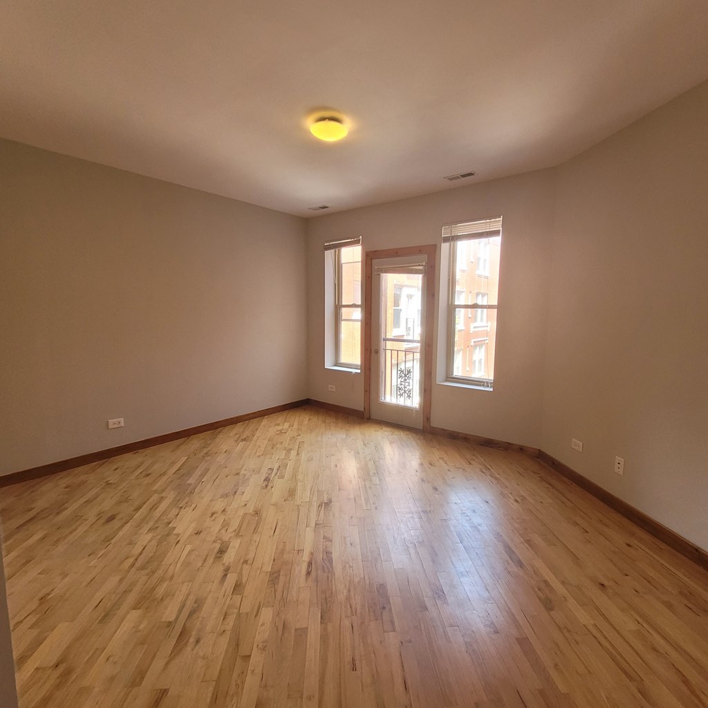 an empty living room with wood floors and a window