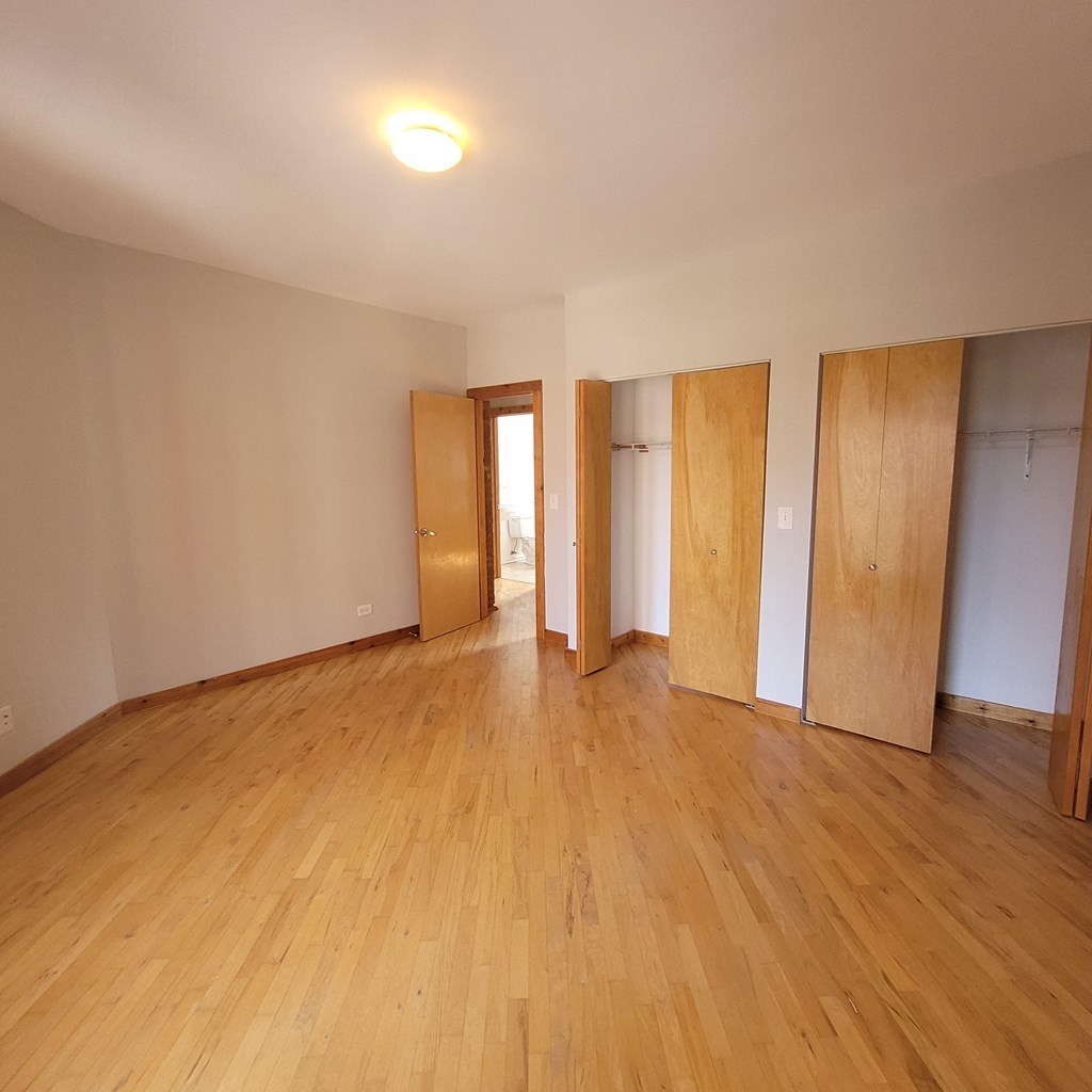 an empty living room with wooden flooring and wooden doors