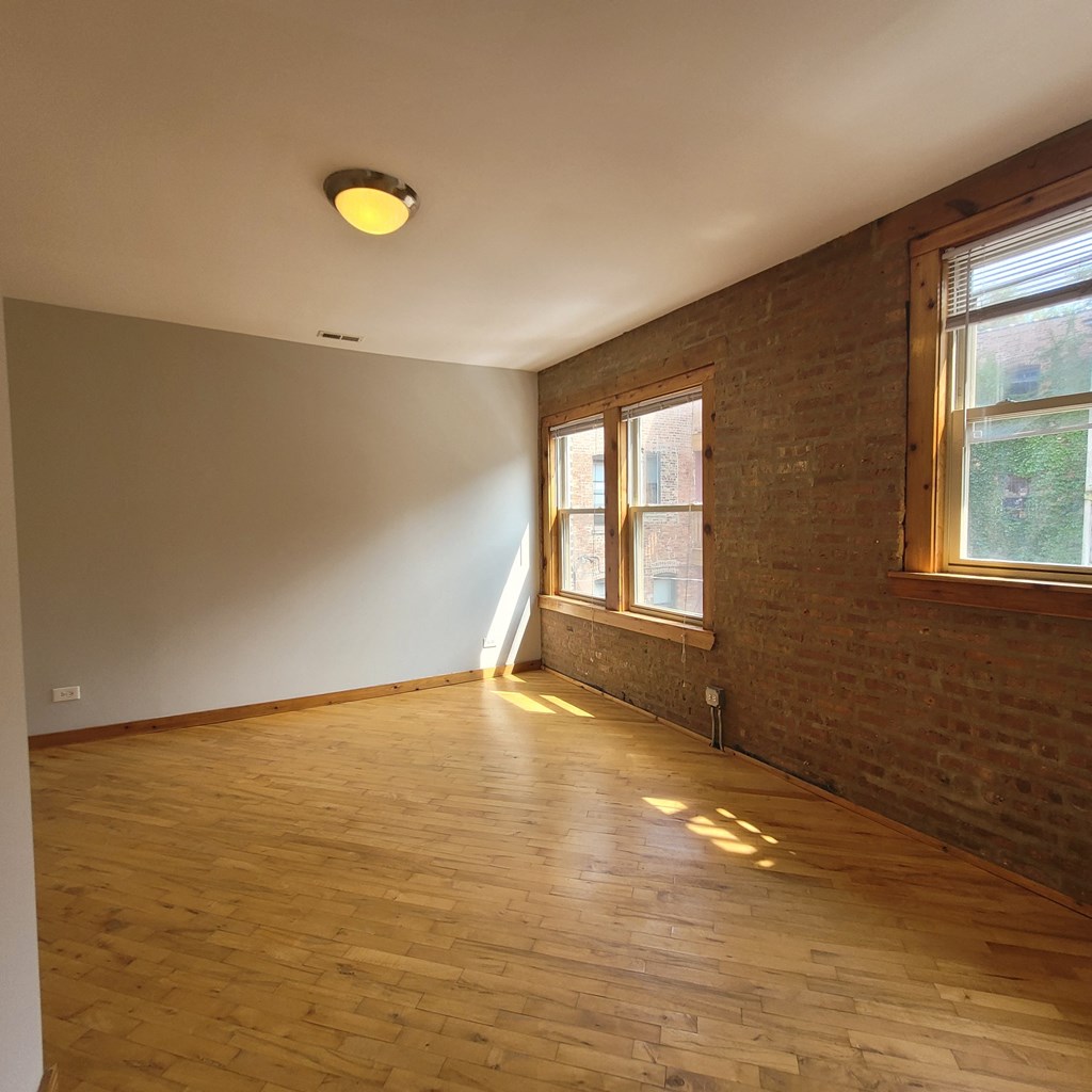 an empty living room with wooden floors and brick walls
