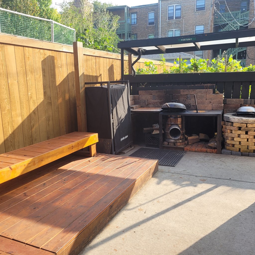 a backyard with a woodfired pizza oven and a wooden bench community area