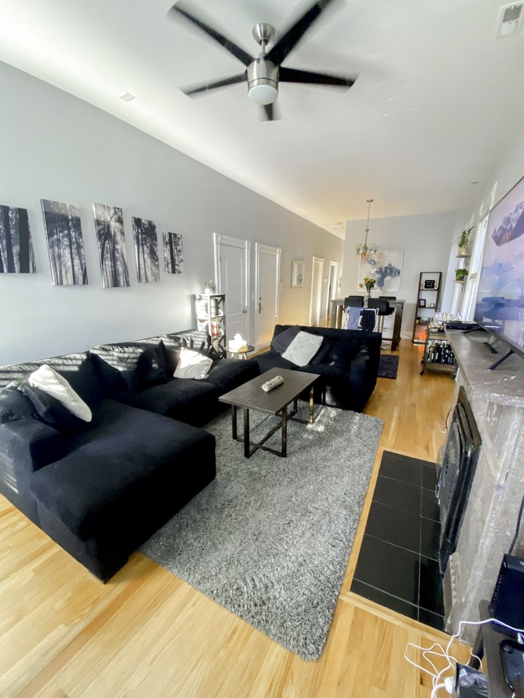 a living room with black furniture and a ceiling fan