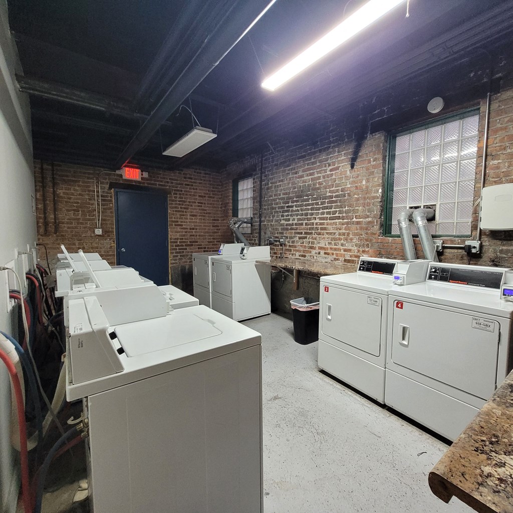 an empty laundry room with four washes and dryers in it
