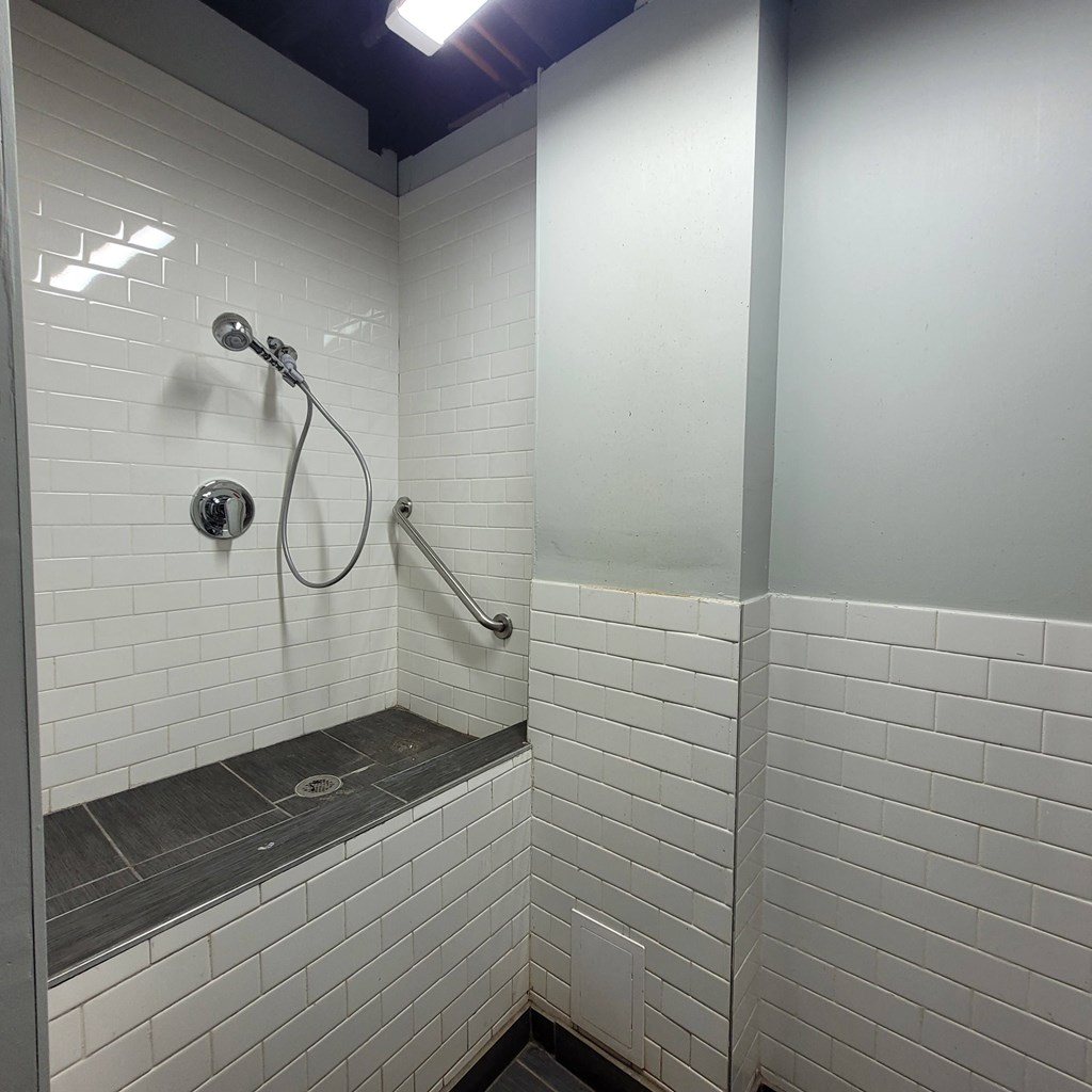 a bathroom with white tiles and a shower head