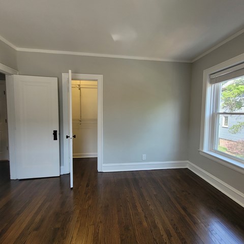 A room with a white door and a window with a view of a tree.