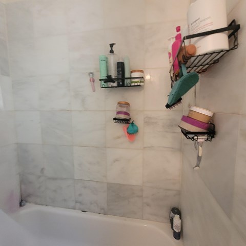 A bathroom with a white tub and a shelf with toiletries.