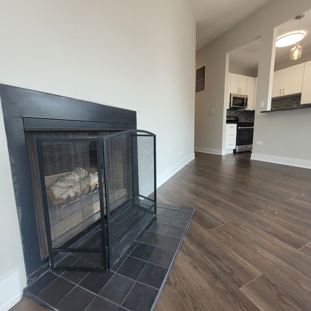 an empty living room with a fireplace with a cage in it
