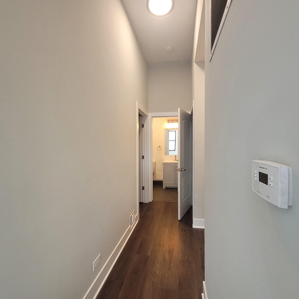 a hallway with a white wall and a door to a bathroom