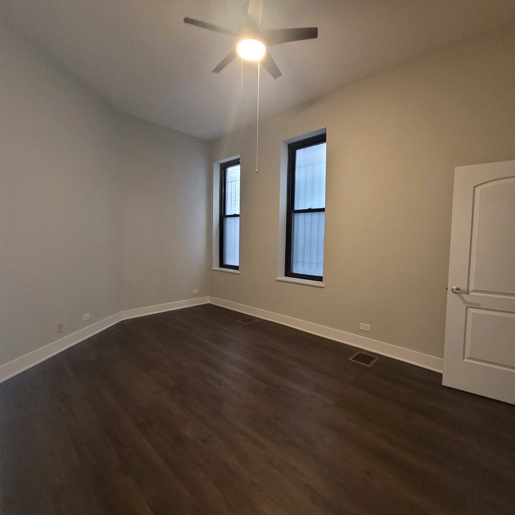 an empty living room with wooden floors and a ceiling fan