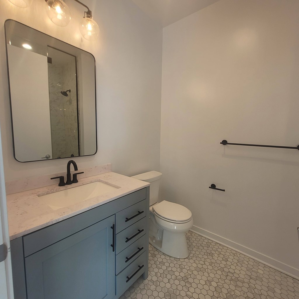 A white toilet sits in a bathroom with a sink and mirror.
