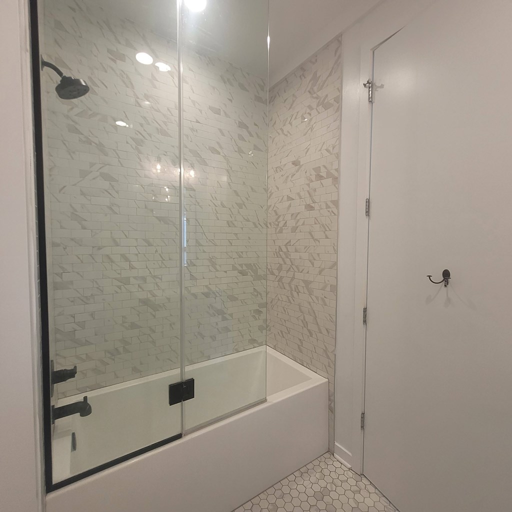 A white tiled bathroom with a glass shower door.
