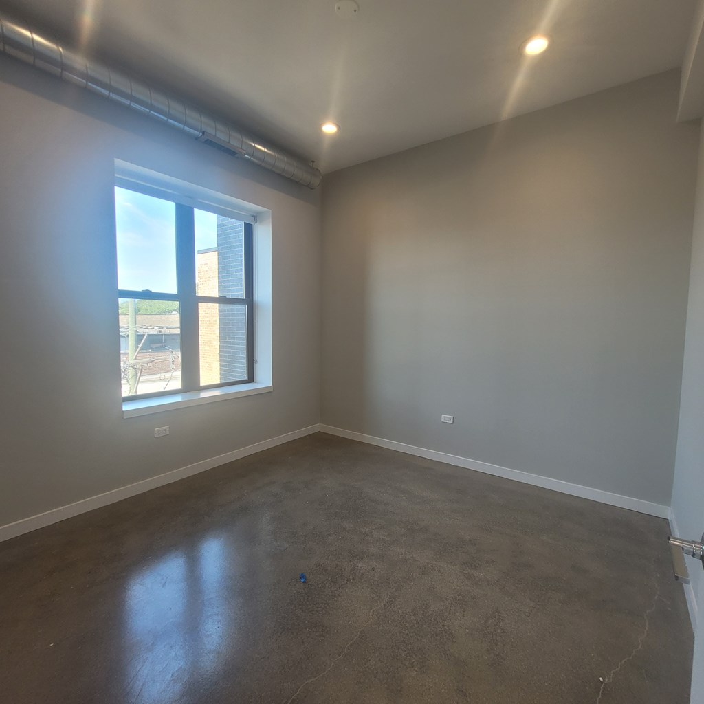A room with a window and a grey floor.