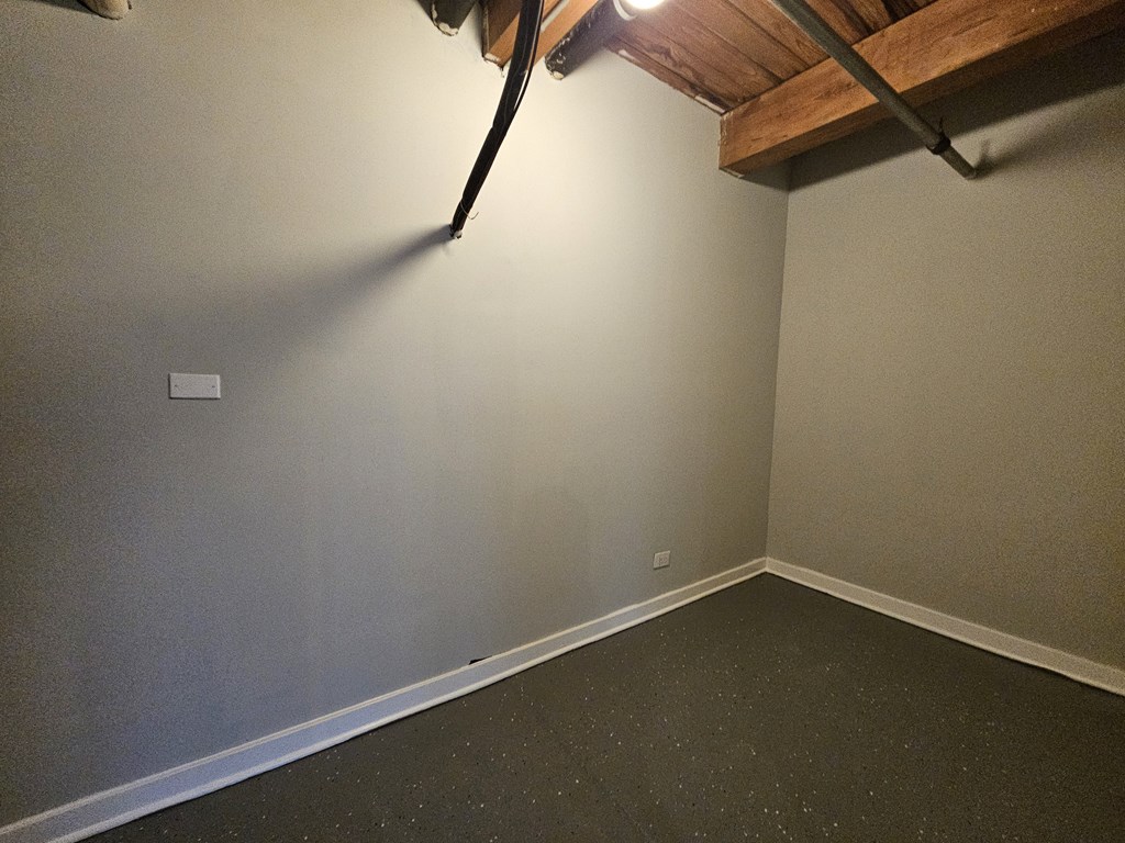 A room with a wooden beam on the ceiling and a light switch on the wall.