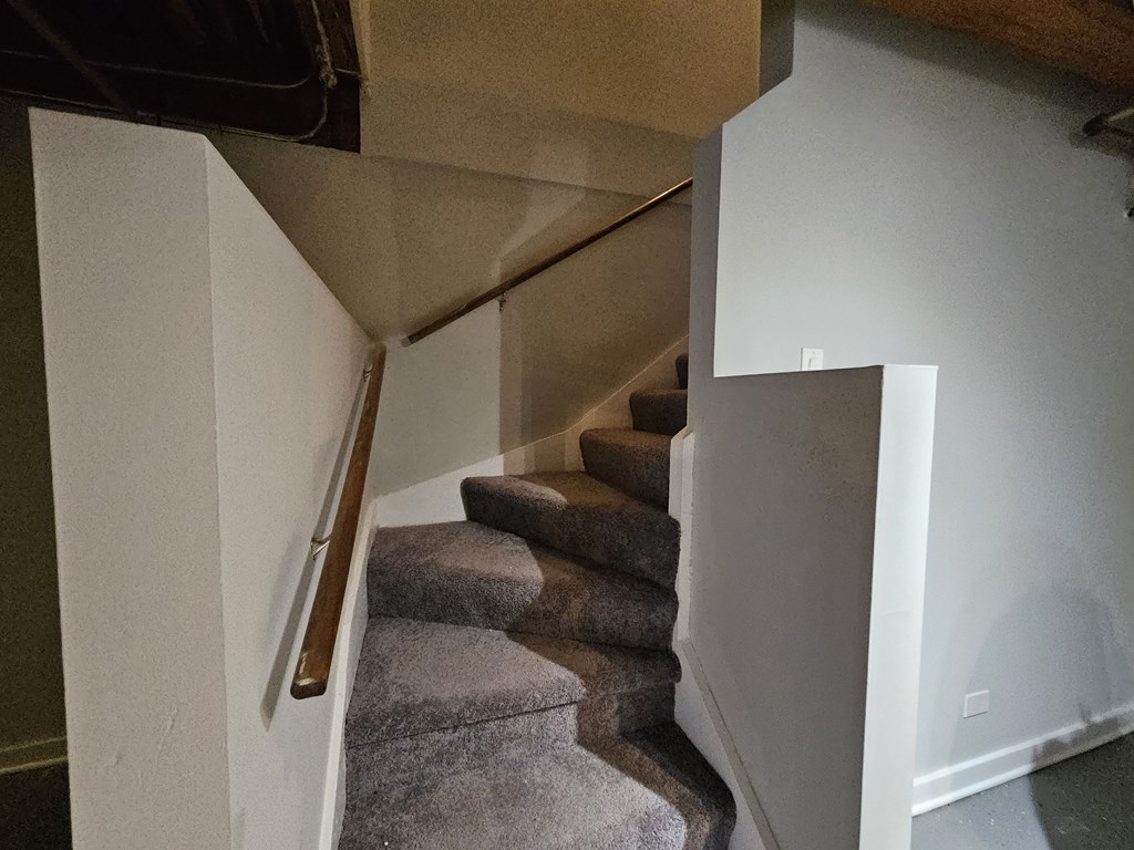 A staircase with a carpeted runner and wooden handrail.