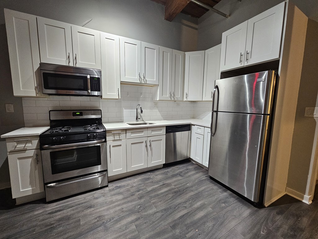 A kitchen with white cabinets and a stainless steel refrigerator.