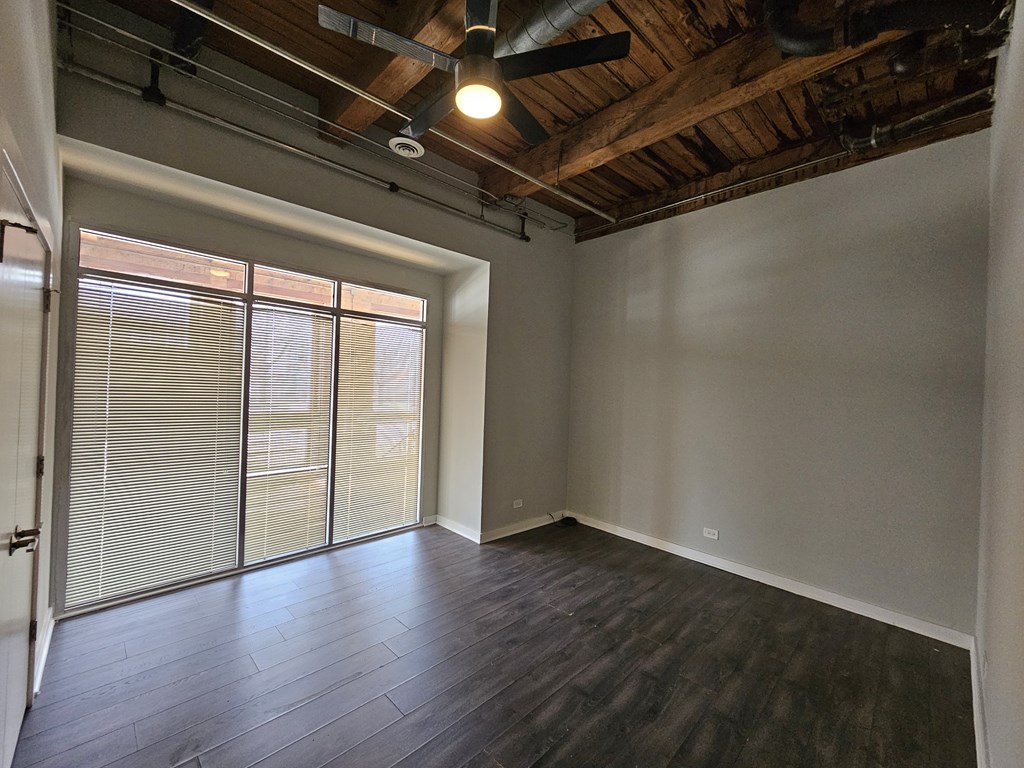 A room with a ceiling fan and sliding glass doors.