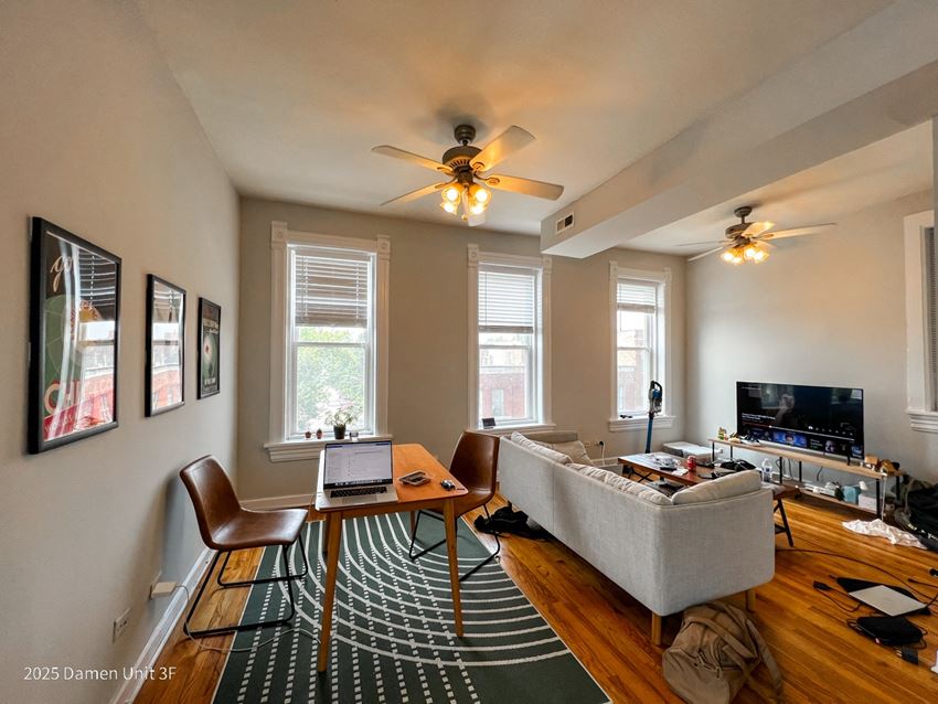a living room with three windows and a ceiling fan