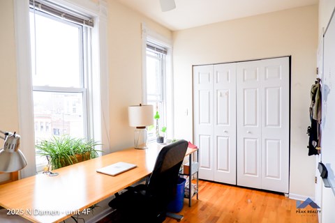 A room with a desk, chair, and a white door.