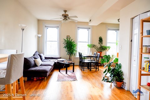 A living room with a couch, chairs, and plants.
