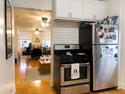 A kitchen with a stove and refrigerator with a towel on the stove that says Food in the Unit.