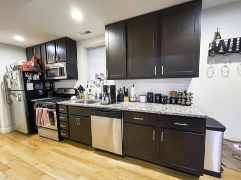 A kitchen with dark brown cabinets and a white tile backsplash.