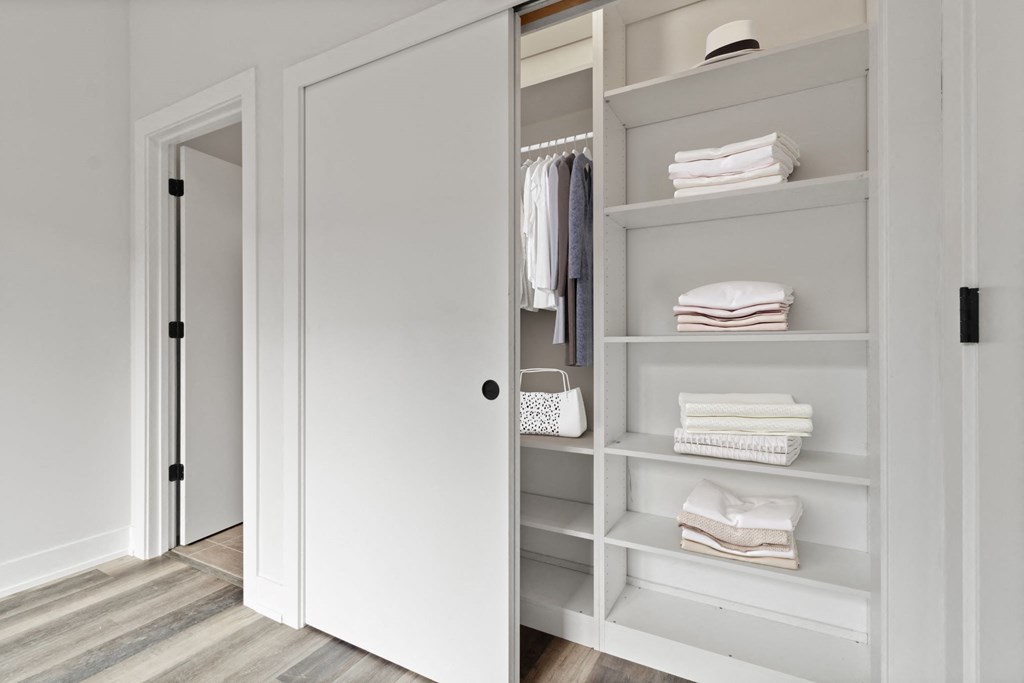 a white walk in closet with white shelves and a white door