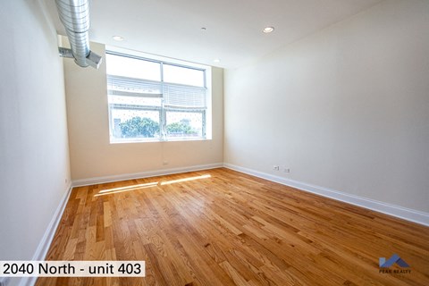 the living room of a home with wood floors and a window