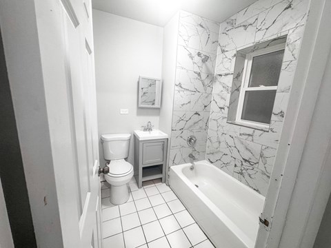 A white bathroom with a toilet, sink, and bathtub.