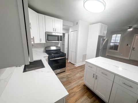 A modern kitchen with white cabinets and stainless steel appliances.
