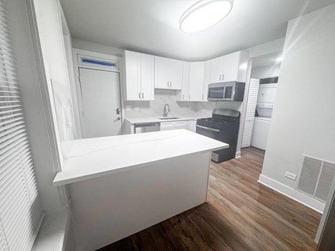 A kitchen with white cabinets and a white island.