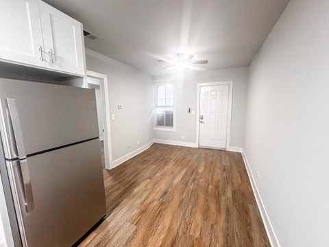 A kitchen with a refrigerator and wooden floors.
