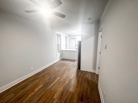 A room with a ceiling fan and wooden flooring.