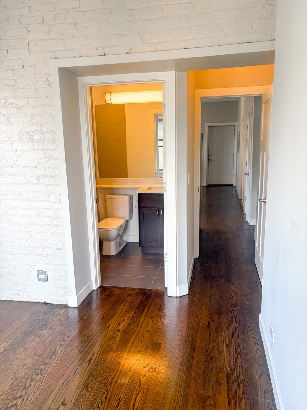 A white bathroom with a toilet and sink is open to a hallway.
