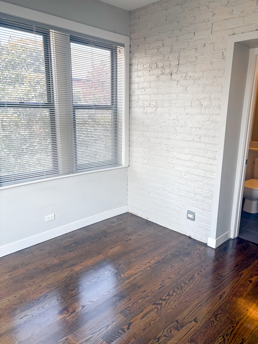 A room with a white brick wall and wooden floors.