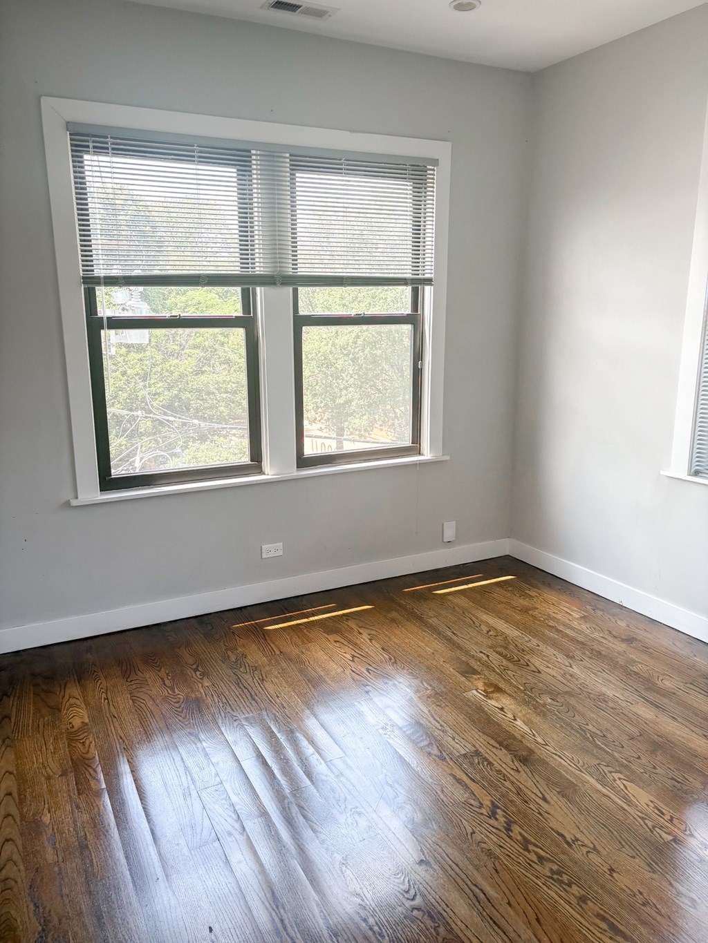 A room with a window and wooden flooring.